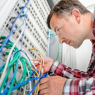 Datatekniker kontrollerar kablar som sitter i en server