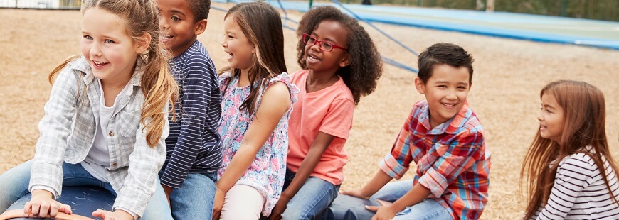 Barn sitter på ett snurrande lekredskap på en skolgård
