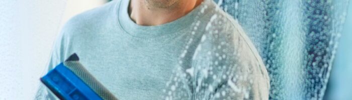 En man putsar fönster i en kontorslokal