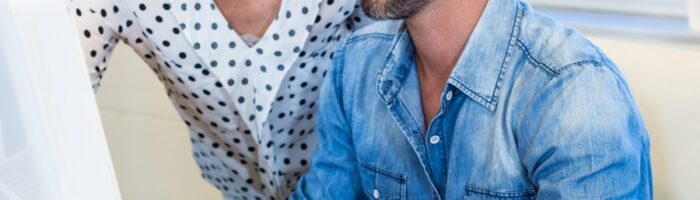 Två kollegor, en man och en kvinna samspråkar vid en datorskärm